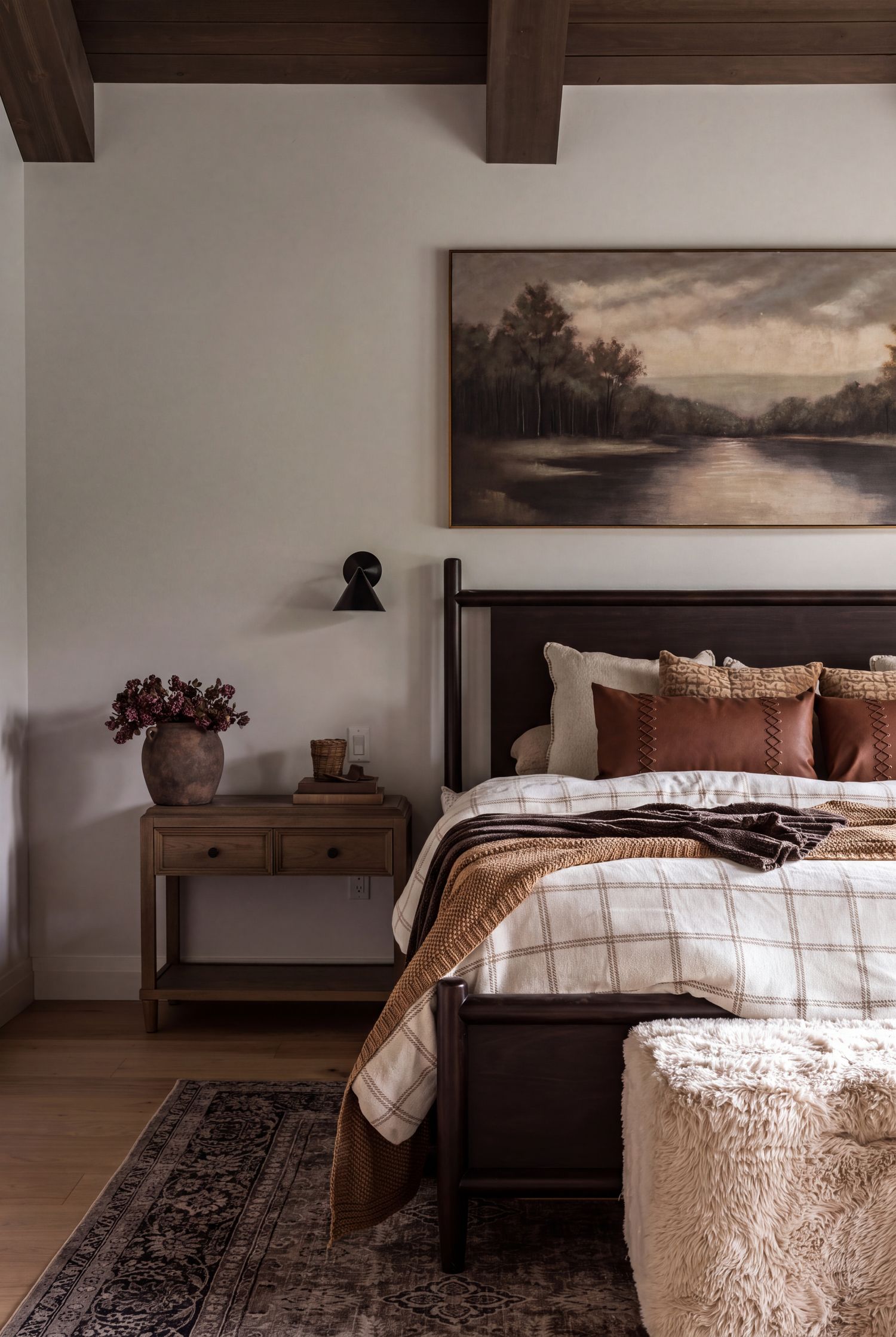 Primary bedroom in a Safe Haven custom home — beamed ceiling, dark wood bed and layered natural textiles