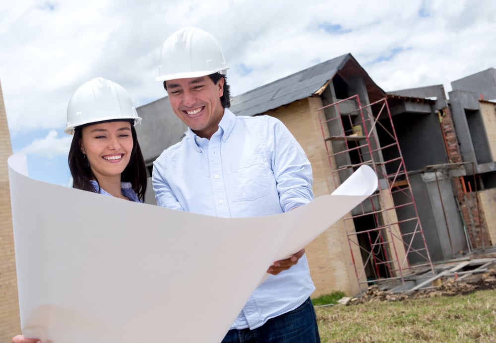 Happy couple looking at blueprints of their house